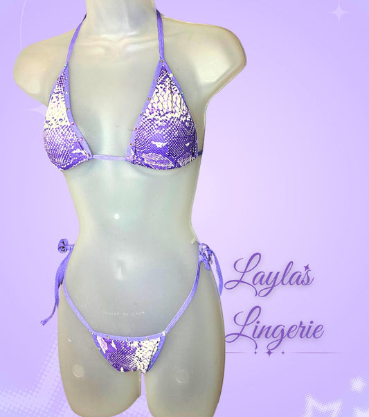 light purple faux snakeskin two piece bikini with rhinestones on the edges, the top is two triangles of cloth  and ties in the back. The bottoms are a low rise thong and tie on the sides